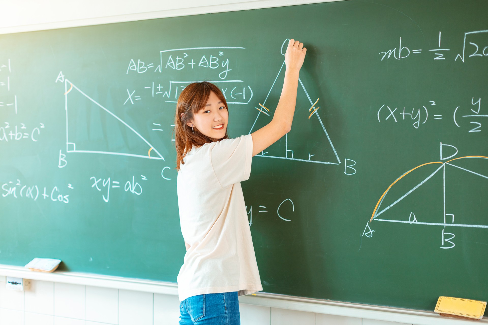 female student in the classroom writing on chalkboard  mathematical equations